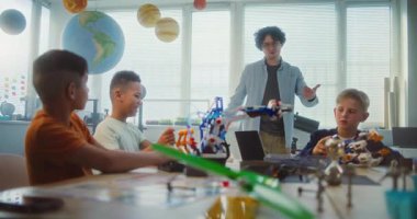 Genç Öğretmen ve Çocuklar, Çok Irklı Sınıfta Toplu Hareketler Yapıyorlar. Robot Bilimi ve Yenilenebilir Enerji Modelleri Keşfeden İlkokul Çocukları, Takım Çalışmasını Kutluyor. BTMM Öğrenme. Yavaş Hareket.