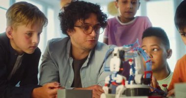 İlkokul öğrencileri Masa 'da oturuyor, Robotik Kol Modeli okuyor. Çok Kültürlü Sınıfta Bilim ve Mühendislik Dersinde Zeki Çocukları Eğiten Öğretmen Grubu. STEM Eğitimi.