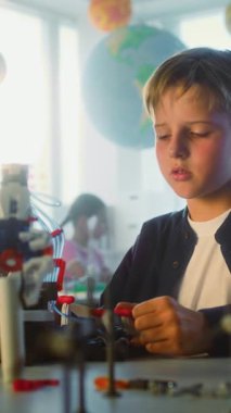 İlkokul öğrencileri fen ve mühendislik dersinde yenilikçi robotik kol modelini inceliyor. Sınıfta Grup İçinde Oturan Zeki Genç Çocuklar. Etkileşimli BTMM Eğitimi. Dikey Çekim.