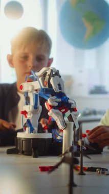İlkokul öğrencileri fen ve mühendislik dersinde yenilikçi robotik kol modelini inceliyor. Çeşitli Akıllı Çocuklar Grup Masasında Oturuyor. Etkileşimli BTMM Eğitimi. Dikey Çekim
