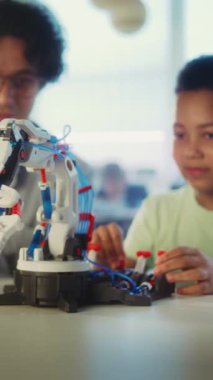 Bilim Dersi: İlköğretim Okulu Öğrenci Robot Kolu Modeli. Modern Sınıfta Akıllı Afro-Amerikan Çocuğu Eğiten Genç Öğretmen. İnteraktif Öğrenme ve BTMM Eğitimi. Dikey Çekim.
