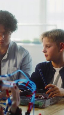 Çeşitli çocuklar ve öğretmenler çok kültürlü sınıflarda STEM projeleri üzerinde birlikte çalışıyorlar. Robot Bilimi ve Yenilenebilir Enerji Modelleri Araştıran İlkokul Öğrencileri. Dikey Çekim.