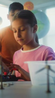 Yetenekli Çocuklar Takımı Robot Kol Modeli Çalışıyor ve Eğleniyor. Çok Irklı Sınıfta İlkokul Çocukları Bilim ve Teknoloji Dersinde. Etkileşimli BTMM Eğitimi. Dikey Çekim.