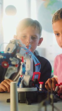 İlkokul öğrencileri Yenilikçi Robotik Kol Modeli üzerine çalışıyor. Modern Sınıfta Bilim ve Mühendislik Dersinde Akıllı Çocuk ve Kız Grubu. Etkileşimli BTMM Eğitimi. Dikey Çekim.