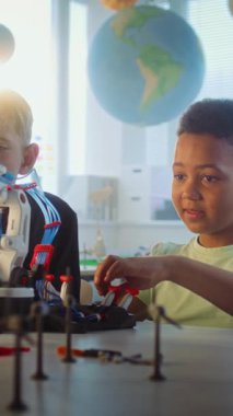 Çok Irklı Yetenekli Çocuklar Masada Oturup Robotik Kollar Modelini Çalışıyor. Modern Sınıfta İlkokul Çocukları Bilim Dersinde. İnteraktif Öğrenme, BTMM Eğitimi. Dikey Çekim.