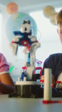 Yetenekli Oğlan ve Kız Robotik Kolları İnceleme Ekibi. İlkokul Çocukları ve Öğretmenleri Bilim ve Teknoloji Dersinde Sınıfta. İnteraktif Öğrenme, BTMM Eğitimi. Dikey Çekim.