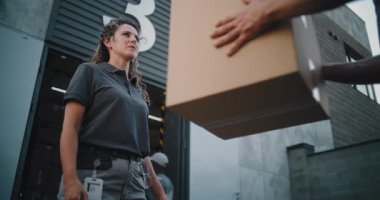 Lojistik Perakende Deposu 'nun dışında: Çevrimiçi Siparişler ve Tanınmayan Meslektaşlar' dan E-Ticari Mallar ile Karton Kutu Alan Kadın İşçi. Teslimat Servisi, Depolama Tesisi 'nde çalışan kadın.