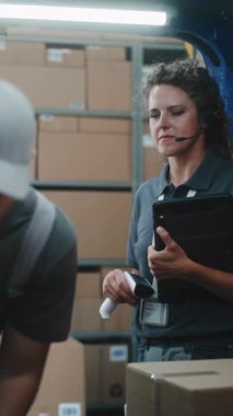 Çoklu etnik kökenli işçiler karton kutuları çevrimiçi siparişlerle, teslimat kamyonundan gelen mallarla yüklüyorlar. Kadın Yönetici Tablet Bilgisayar ve Barkod Tarayıcı kullanıyor. Lojistik Deposu 'nun dışında. Dikey Çekim.