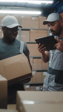 Lojistik Dağıtım Deposu 'nun dışında muhtelif çalışanlar karton kutularla kargo kamyonu boşaltıyorlar. Dijital Tablet kullanarak Yönetici Tarayıcı Paketleri. E-Commerce Online Emirler. Dikey Çekim.