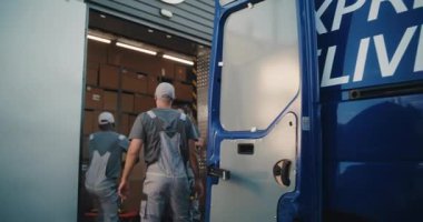 Lojistik Dağıtım Deposu 'nun dışında çeşitli çalışanlar karton kutuları teslimat kamyonunda online siparişlerle yüklüyor. Dijital Tablet kullanan Kadın Yönetici. Ekspres Teslimat Servisi.