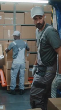 Lojistik Deposu 'nun dışında çeşitli çalışanlardan oluşan bir ekip karton kutularla teslimat kamyonu, online siparişler, e-ticaret ürünleri. Teslimat Servisi, Depolama Tesisi 'nde çalışıyorum. Dikey Çekim.