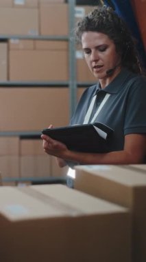Çoklu etnik kökenli işçiler karton kutuları çevrimiçi siparişlerle, teslimat kamyonundan gelen mallarla yüklüyorlar. Kadın Yönetici Tablet Bilgisayar ve Barkod Tarayıcı kullanıyor. Lojistik Perakende Deposu. Dikey Çekim.