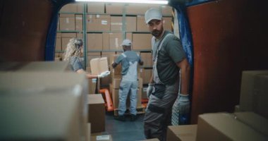 Lojistik Deposu 'nun dışında çeşitli çalışanlardan oluşan bir ekip karton kutular, online siparişler, alışverişler ve E-ticaret ürünleriyle kargo kamyonu boşaltıyordu. Teslimat Servisi, Depolama Tesisi 'nde çalışıyorum..