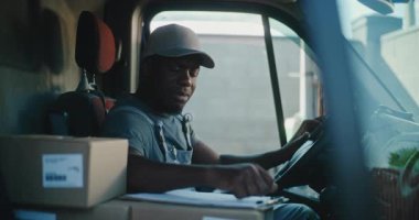 Afro-Amerikan kargo kamyonu şoförü Dijital tablet kullanarak arabada oturuyor, evrakları dolduruyor. Ekspres Teslimat Servisi 'nde çalışan ve Çevrimiçi Siparişler, Satın Alım, E-Ticaret, Gıda