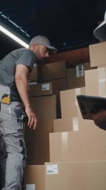 Lojistik Deposu 'nun dışında, erkek çalışan teslimat kamyonu karton kutular, online siparişler, e-ticaret ürünleri. Afro-Amerikan Yöneticisi Dijital Tablet kullanıyor. Ağır çekim. Dikey Çekim.
