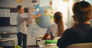 BTMM Yenilenebilir Enerji Sınıfı: Dünya Modelini Kullanan İlkokul Öğrencilerine Enerji Kaynaklarını Açıklayan Kadın Öğretmen. Modern Sınıfta Farklı Çocuklar Ekoloji ve Bilim Öğreniyor. Yavaş Hareket.