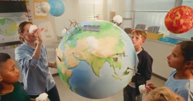 STEM Bilim Dersi: İlkokul Çocukları Yenilenebilir Enerji Araştırması. Akıllı Çeşitli Çocukları Eğiten Kadın Öğretmen Dünya 'yı Minyatür Rüzgar Türbinleri ve Güneş Panelleri Modelleri ile Kullanıyor. Yüksek Açı.