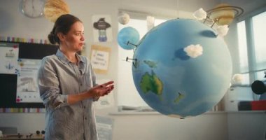 Sınıfta Dünya Gezegeni 'nin Modelini kullanarak Fen Eğitimi ve Yenilenebilir Enerji Kaynakları Dersleri. Dünya 'daki Rüzgâr Türbinleri ve Güneş Panelleri' nin minyatür 3D modelleri. Orta Çekim.