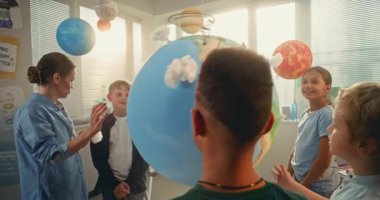 Bilim dersi: İlkokul çocukları yenilenebilir enerji üzerinde çalışıyorlar. Çeşitli Çocuklar Takımı 'nı Eğiten Kadın Öğretmen Minyatür 3 boyutlu Rüzgar Türbinleri ve Güneş Panelleri Modelleri ile Dünyayı Kullanıyor. STEM Eğitimi.