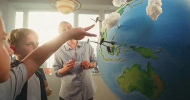 İlköğretim Okulu Öğrencileri Yenilenebilir Enerji Kaynakları Öğreniyor. Dünya Modelini Rüzgâr Türbinleri ve Güneş Panelleri Modelleri ile kullanan Zeki Çocuklar Ekibi 'ne Ekolojiyi Açıklayan Kadın Öğretmen.