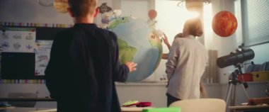 Etkileşimli bilim dersi: Dünya modelini kullanan zeki çocukları eğiten kadın öğretmen. Modern Çoklu Etnik Sınıflar Odasında İlkokul Çocukları Yenilenebilir Enerji ve Güneş Sistemi Okuyor. STEM Eğitimi.