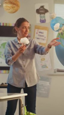 İlkokul kızı, Dünya Modelini Kullanarak Sınıfın Önündeki Yeşil Enerji Kaynaklarını Sunar. Çevre Bilimi dersi sırasında zeki çocukları eğiten kadın öğretmen. BTMM Eğitim. Dikey Çekim.