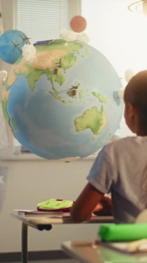 BTMM Yenilenebilir Enerji Sınıfı: Dünya Modelini Kullanan İlkokul Öğrencilerine Enerji Kaynaklarını Açıklayan Kadın Öğretmen. Modern Sınıfta Ekoloji Öğrenen Çocuklar. Ağır çekim. Dikey Çekim.