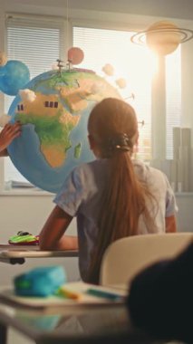 Akıllı Çocukları Eğiten Kadın Öğretmen Dünya Modelini Kullanıyor. Modern Çoklu Etnik Sınıflar Odasında İlkokul Çocukları Yenilenebilir Enerji ve Güneş Sistemi Okuyor. BTMM Eğitim. Ağır çekim. Dikey Çekim.