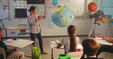 Bilim dersi: Dünya Gezegeni Modelini Kullanan Akıllı Çocukları Eğiten Kadın Öğretmen. Modern Çoklu Etnik Sınıflar Odasında İlkokul Çocukları Yenilenebilir Enerji ve Güneş Sistemi Okuyor. STEM Eğitimi.