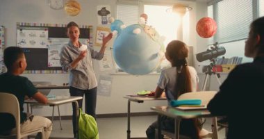 Çok Irklı Sınıfta Bilim Dersinde Akıllı Çocukları Eğiten Bayan Öğretmen. İlkokul çocuğu, Dünya Modelini Kullanarak Sınıfın Önündeki Yeşil Enerji Kaynaklarını Sunar. BTMM Eğitim. Doli Vuruşu.