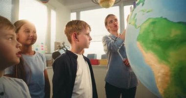 STEM Bilim Dersi: Akıllı Çeşitli Çocukları Eğiten Kadın Öğretmenler Dünya 'yı Minyatür 3 boyutlu Rüzgar Türbinleri ve Güneş Panelleri Modelleri ile Kullanıyor. İlkokul Çocukları Yenilenebilir Enerji ve Ekoloji okuyor.