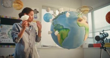 Modern Sınıfta Bilim Dersinde Akıllı Çocukları Eğiten Bayan Öğretmen. İlkokul çocuğu, Dünya Modelini Kullanarak Sınıfın Önündeki Yeşil Enerji Kaynaklarını Sunar. BTMM Eğitim. Doli Vuruşu.