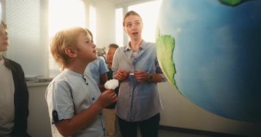 STEM Bilim Dersi: İlkokul çocukları Yenilenebilir Enerji ve Ekoloji okuyor. Dünya 'yı Minyatür Rüzgar Türbinleri ve Güneş Panelleri Modelleri ile Kullanan Akıllı Çeşitli Çocukları Eğiten Kadın Öğretmenler.