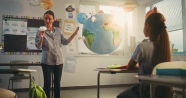 Modern Sınıfta Bilim Dersinde Akıllı Çocukları Eğiten Bayan Öğretmen. İlkokul çocuğu, Dünya Modelini Kullanarak Sınıfın Önündeki Yeşil Enerji Kaynaklarını Sunar. Etkileşimli BTMM Eğitimi.