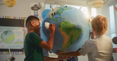 Yenilenebilir Enerji BTMM Sınıfı: İlkokul öğrencileri Dünya 'ya Bulutların Minyatür Modelleri Ekliyor. Modern Sınıfta Akıllı Çeşitli Çocuklara Bilim ve Enerji Kaynaklarını Açıklayan Bayan Öğretmen.