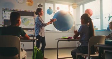 BTMM Yenilenebilir Enerji Sınıfı: Dünya Gezegeni Modelini Kullanan İlkokul Öğrencilerine Enerji Kaynaklarını Açıklayan Kadın Öğretmen. Modern Sınıfta Çeşitli Çocuklar Coğrafya ve Bilim Öğreniyor.