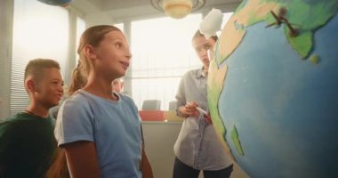 STEM Bilim Dersi: Akıllı Okul Kızı, Dünya 'yı 3 boyutlu Rüzgar Türbinleri ve Güneş Panelleri Modelleri ile Yenilenebilir Enerji Kaynaklarını Sunar. İlkokul Çocukları Bayan Öğretmenle Ekoloji okuyor.