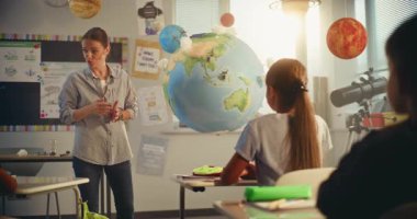 BTMM Yenilenebilir Enerji Sınıfı: Dünya Modelini Kullanan İlkokul Öğrencilerine Enerji Kaynaklarını Açıklayan Kadın Öğretmen. Modern Sınıfta Farklı Çocuklar Ekoloji ve Bilim Öğreniyor. Yavaş Hareket.