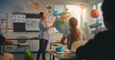 Bilim dersi: Dünya modelini kullanan zeki çocukları eğiten kadın öğretmen. Modern Çoklu Etnik Sınıflar Odasında İlkokul Çocukları Yenilenebilir Enerji ve Güneş Sistemi Okuyor. BTMM Eğitim. Yavaş Hareket.