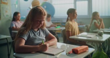 Modern Sınıfta Coğrafya Dersinde İlkokul Kızları Not Defterinde Yazıyor 'a odaklan. Masalarda oturan, ekoloji okuyan, öğretmenden ders dinleyen zeki çeşitli çocuklardan oluşan bir takım.