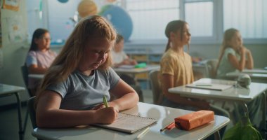 Modern Sınıfta Coğrafya Dersinde İlkokul Kızları Not Defterinde Yazıyor 'a odaklan. Masalarda oturan, ekoloji okuyan, öğretmenden ders dinleyen zeki çeşitli çocuklardan oluşan bir takım.