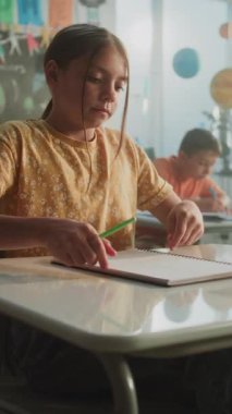 Masalarda oturan ilkokul öğrencileri, Sınıfta coğrafya veya fen sınavı yazıyorlar. Okul Sınavı Sürecinde Genç Kız ve Oğlanları Yürüyen ve Denetleyen Kadın Öğretmen. Dikey Çekim.