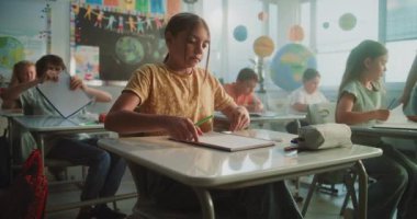 Masalarda oturan ilkokul öğrencileri, Modern Sınıfta Sınav ya da Coğrafya veya Bilim Üzerine Ders Yazıyorlar. Okul Sınavı Sürecinde Genç Kız ve Oğlanları Yürüyen ve Denetleyen Kadın Öğretmenler