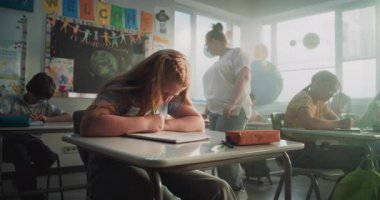 Modern Sınıfta Konsantre İlkokul Çocukları Coğrafya veya Ekoloji Üzerine Okul Sınavı Yazıyor. Masalar Arasında Yürüyen Kadın Öğretmenler Sınav Sürecinde Çeşitli Çocukları Kontrol Ediyor.