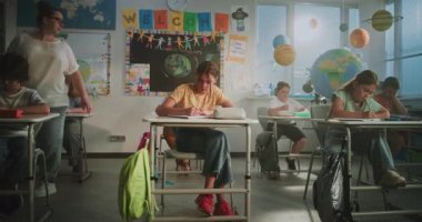 Modern Sınıfta Konsantre İlkokul Çocukları Coğrafya veya Ekoloji Üzerine Okul Sınavı Yazıyor. Masalar Arasında Yürüyen Kadın Öğretmenler Sınav Sürecinde Çeşitli Çocukları Kontrol Ediyor.