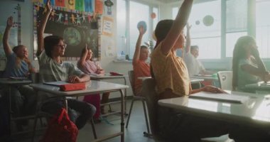 İlkokul öğrencileri masada oturuyor, öğretmenden ders dinliyor, doğru cevabı vermek için ellerini kaldırıyor. Modern Sınıfta Bilim, Coğrafya okuyan Akıllı Çeşitli Çocuklar Takımı.