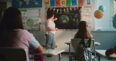 Bayan Öğretmen İlkokul Öğrencilerine Yenilenebilir Enerji Kaynakları Konusunda Ders Veriyor. Modern Renkli Sınıfta Masalarda oturan, Ekoloji okuyan, Öğretmeni Dinleyen Zeki Çeşitli Çocuklar.