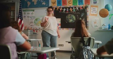 Modern Sınıfta İlkokul Çocuklarına Ekoloji Konulu Kadın Öğretmenlik Dersi. Masalarda oturan, Yenilenebilir Enerji Kaynakları öğrenen, Öğretmen 'i dinleyen bir grup genç kız ve erkek..