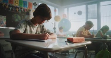 Modern Sınıfta Oturan ve Yenilenebilir Enerji Kaynakları Sınavı Yazan İlkokul Öğrencileri. Masaların Arasında Yürüyen Bayan Öğretmen, Okul Sınavı Sürecinde Genç Erkek ve Kızları Kontrol Etmek