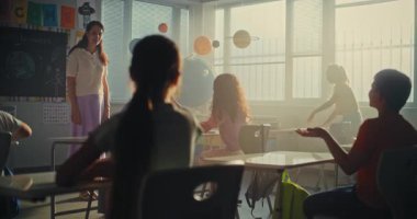 İlkokul çocukları ders için hazırlanıyor, okul malzemelerini modern sınıftaki masalara diziyor. Okulun Başında Çeşitli Çocuklar Kadın Öğretmenler Grubu 'nu selamlıyorum. Yavaş Hareket.